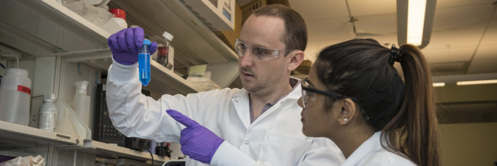 Intern being shown vial in lab from coworkers