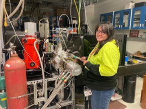 Hannah poses, smiling, while working in the lab.