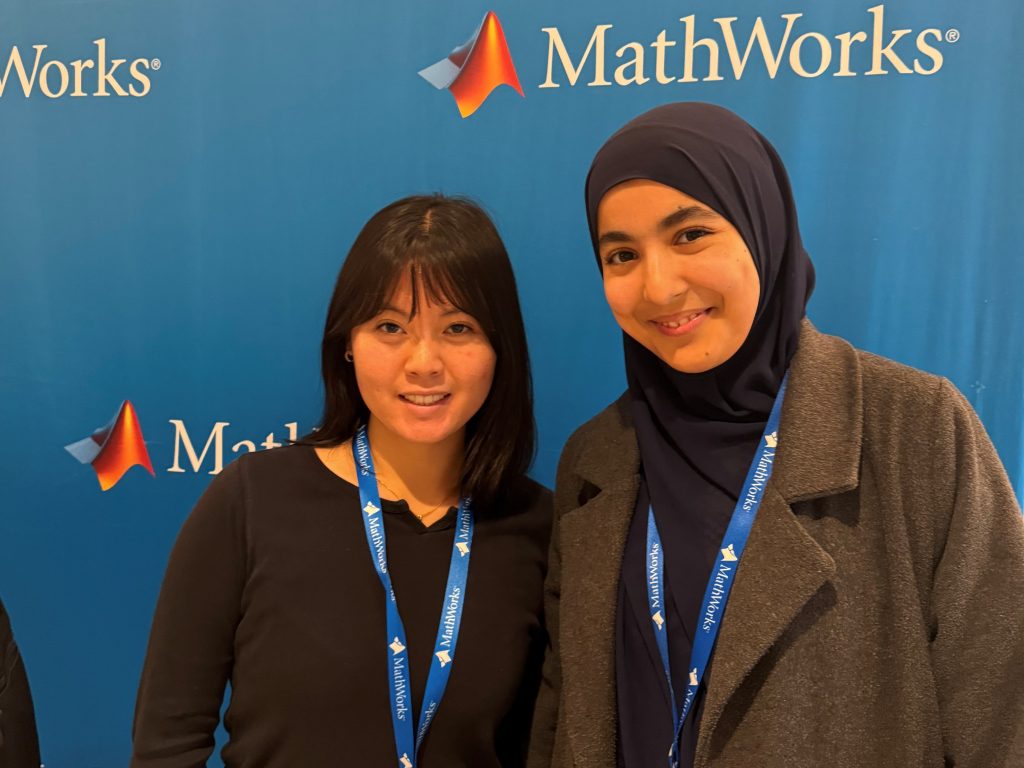 MIT students Salma Bouzit ’27, Course 6, and Anne Christiono ’27, Course 6-3, pose in front of the MathWorks Women in Tech Trek event backdrop.