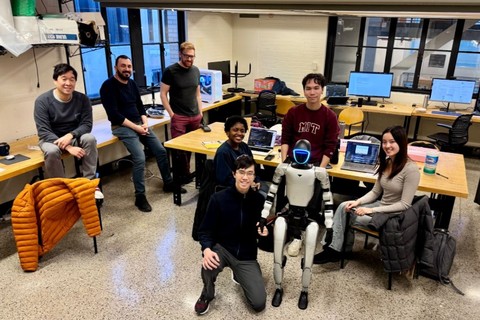 Employees and micro-interns gather in the lab around a robot.