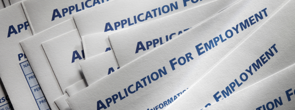 a stack of papers with "application for employment" written on them