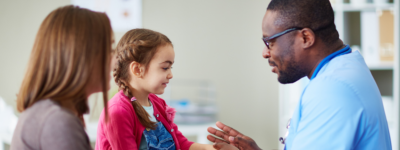 A man in scrubs smiles at a young patient.