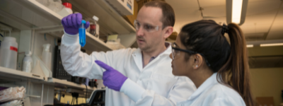 Lab workers showing vial to one another