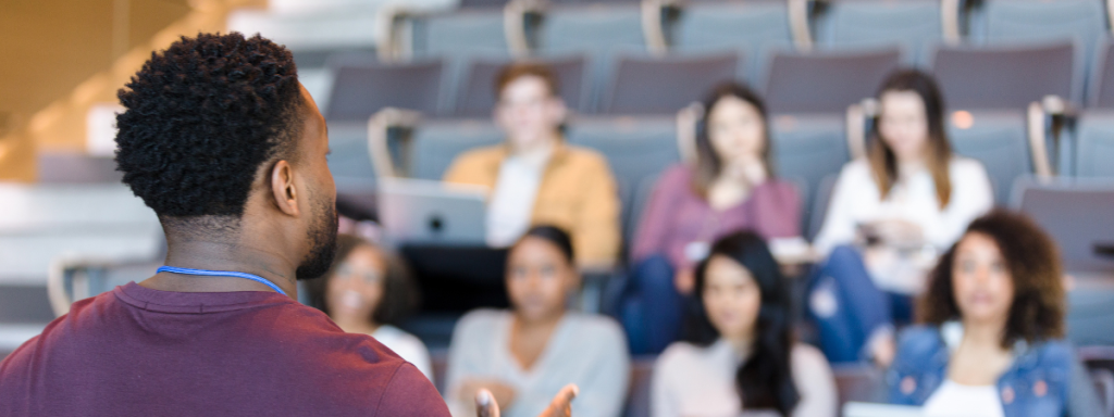 A professor faces a small class, lecturing.