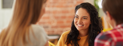 A group of people smile as they talk to each other in a casual setting.