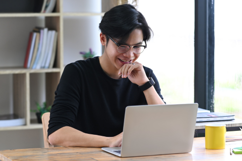 A person smiles while working on their laptop.
