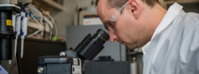 Lab worker looking through microscope