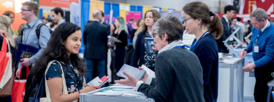 Person at career fair booth talking to employers and recruiters.