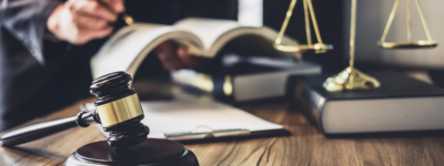open book in background with gavel and balance in foreground