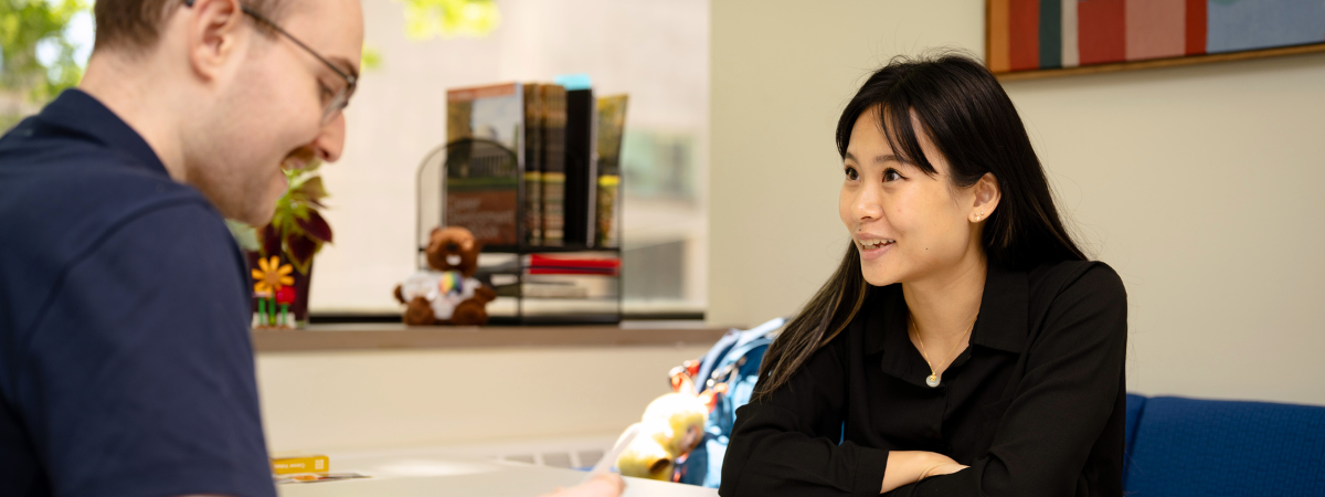 A career advisor meets with a student, both smiling warmly.